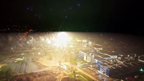 Drone aerial view of fireworks exploding above a city at night, with red smoke Stock Footage 333032346