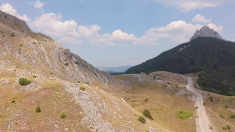 Drone Aerial View Flying Along Mountain Ridge with Winding Dirt Road  Vídeos de archivo 343675045