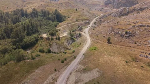Drone Aerial View Flying Over Winding Gravel Road Through Mountain Valley  Stock Footage 343675672
