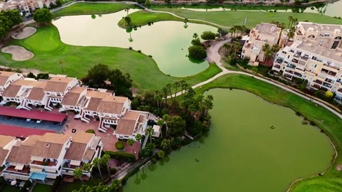 Drone aerial view of golf course, residential buildings, and green water pond Stock Footage 311358029