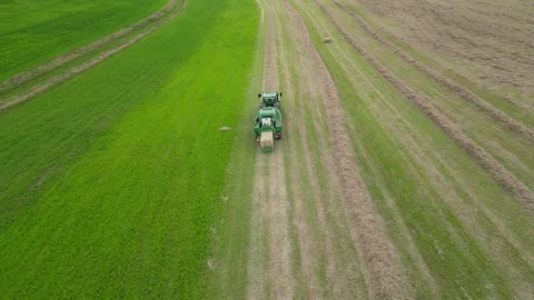 Drone Aerial view of John Deere tractor working in a field baling hay Stock Footage 276963236