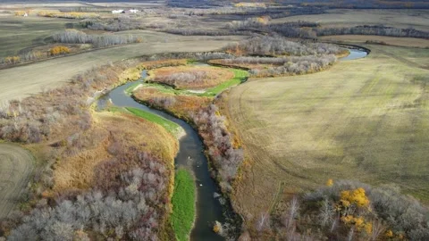 Drone aerial view looking down on a winding river cutting through autumn colored Stock Footage 319595708