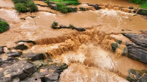 Drone aerial view of muddy river cascading over rocky falls. Stock Footage 310708387