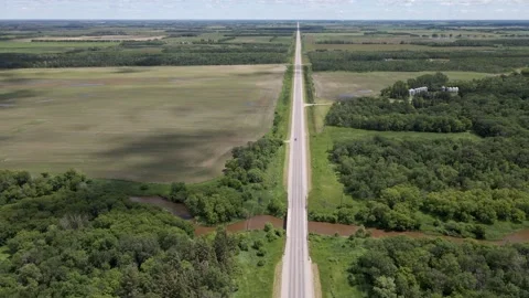 Drone aerial view of a straight paved road cutting across an agricultural landsc Stock Footage 278682877