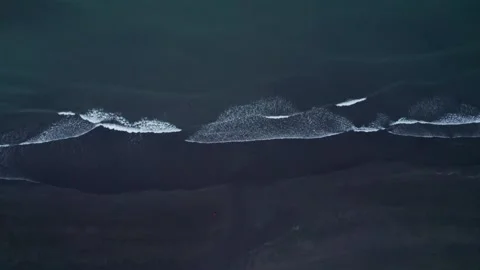 Drone Along Black Sand Beach at Dusk While Girl in Orange Jacket Walks Stock Footage 258508705