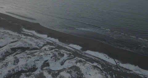 Drone Angle Above a Snowy Black Sand Beach Stock Footage 309326377