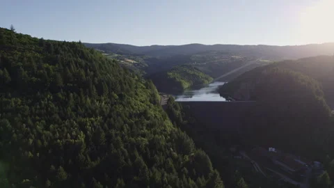 Drone Approach to Dam Blocking Lake Surrounded by Forest at Sunset Stock Footage 315619663