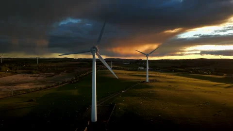 Drone approach to wind turbines over Scottish farmland at sunset Видео 335473253