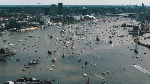 Drone approaches and pans right over sailboats departing Amsterdam Stock Footage 317143420