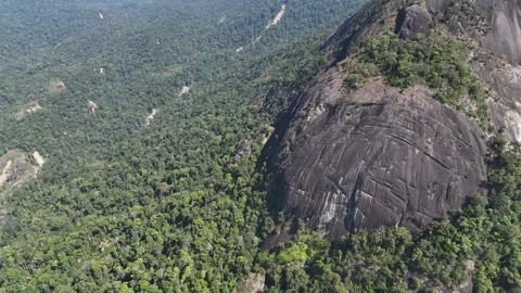 Drone approaching giant rock formation from distance over forested mountain 動画素材 336956558
