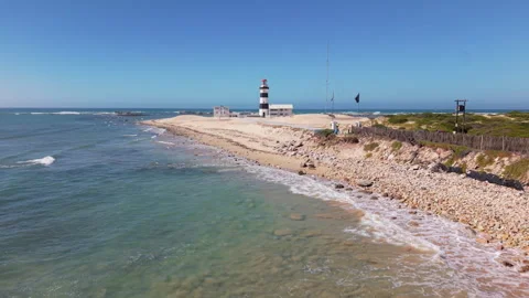 Drone Approaching Lighthouse Along Road with Ocean, Waves, and Cyclist Riding To Stock Footage 306314676