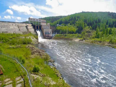 Drone approaching an old hydroelectric power plant with rapid flow of water Vidéo 77490070