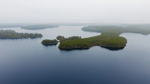 Drone approaching small islands with dense forest in a lake with foggy horizon Video stock 126081296