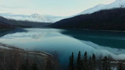 Drone is approaching the snow-capped mountains reflected in a calm river Video stock 131257487