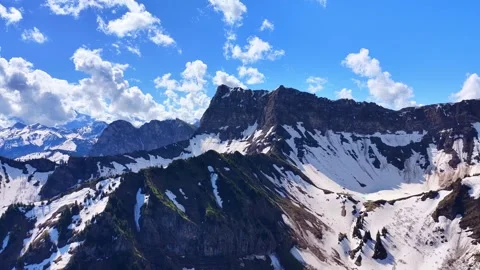 Drone approaching snowy alpine cliffs in spring landscape Stock Footage 336334715