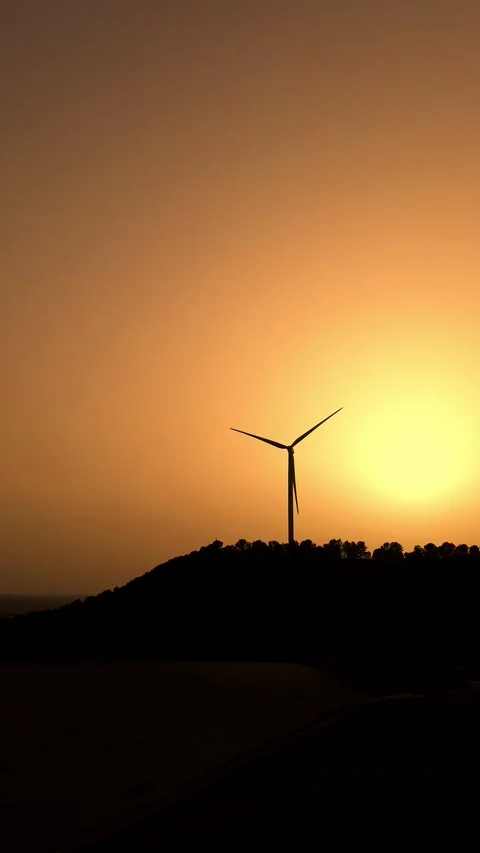 Drone approaching wind turbine at sunset in hazy sky – renewable energy Stock Footage 331284268