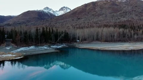 Drone is approaching the winter forest on the shore of the mirror lake Video stock 131258904