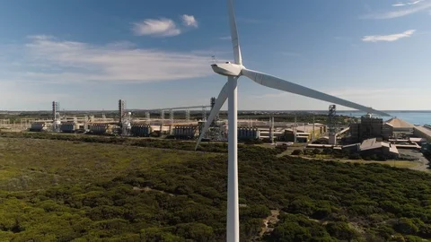 Drone ascending behind wind turbine with aluminum smelter in background. Stock Footage 88261168
