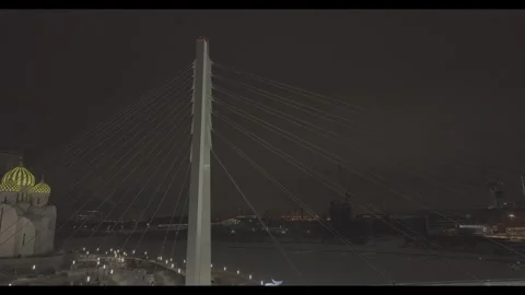Drone ascending near illuminated cable bridge over snowy river at night Stock Footage 320304570