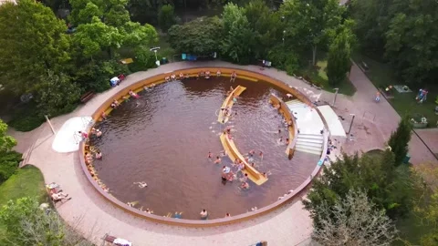 Drone Ascending Over Circular Pool Surrounded by Trees with People Bathing. Stock Footage 305244934