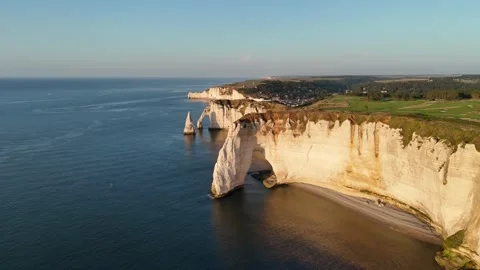 Drone ascending over Etretat white cliffs at golden hour with natural stone arch Stock Footage 346477128