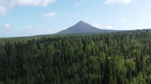 Drone Ascending Over Forest with View of Isolated Sharp‑Topped Mountain Video stock 313364646