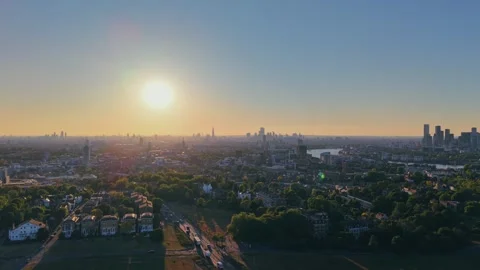Drone ascending over grassy park at golden hour with urban skyline Stock Footage 309769047