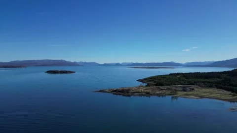 Drone ascending over lake and rocky cliffs in Scotland 動画素材 334458410