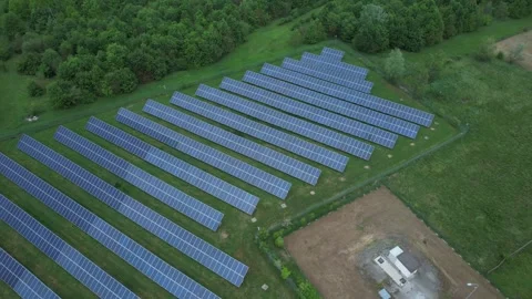 Drone ascending over large solar farm with photovoltaic panels beside forest 스톡 동영상 330915947