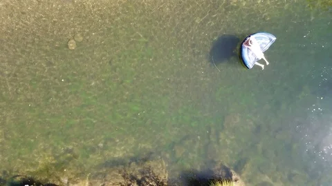 Drone ascends above a small river while people lounge on rafts Stock Footage 95162316