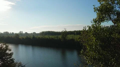 Drone ascends above trees and lake with fishermen on a shore in sunny autumn day Stock Footage 263149755