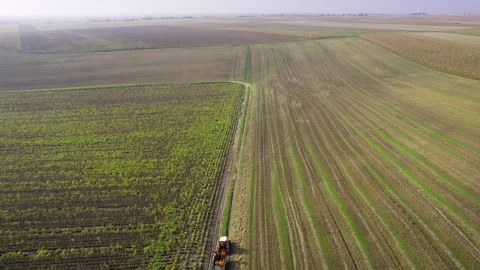 Drone ascends and captures tractor and vast agricultural land Stock Footage 262464722