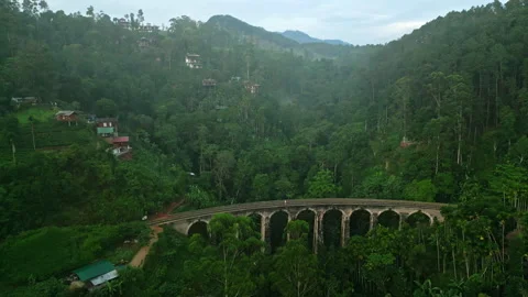 Drone ascends on Nine Arch Bridge at sunrise in Sri Lanka. Solo traveler walks Stock Footage 275112334