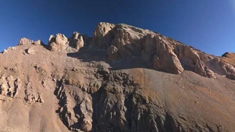 Drone ascent above rocky cliffs revealing alpine landscape Stock Footage 336334373