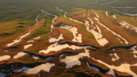 Drone backward flight above alpine ridges with melting snowfields and rolling Stock Footage 336980570