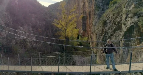 Drone backward flight from suspension bridge and senior hiker Stock Footage 124388770