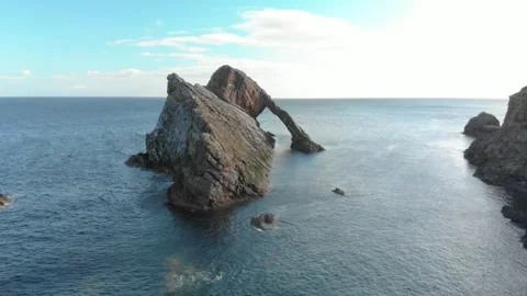 Drone Backwards Tracking Shot Retreating from Bow Fiddle Rock Sea Arch in Calm Stock Footage 336755086