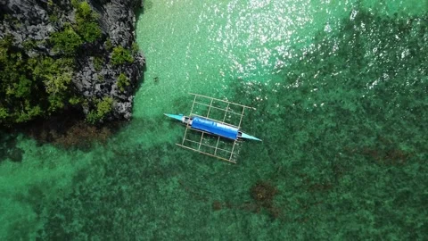 Drone Bird’s Eye View 4K: Traditional Outrigger Boat Anchored by Limestone Cliff Stock Footage 343475490