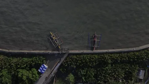 Drone Bird’s Eye View 4K: Traditional Outrigger Boats Docked at Sea Wall Stock Footage 343505624