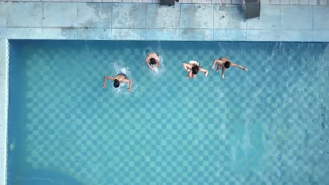 Drone bird's eye view of several friends jumping into a swimming pool on a sunny 스톡 동영상 161964909