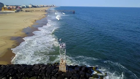 Drone cam circles the jetty point near the inlet in Ocean City MD on a clear day Stock Footage 89450539