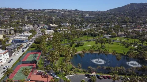 Drone cam over La Jolla Beach and Tennis Club palm trees and fountains Stock Footage 97163501