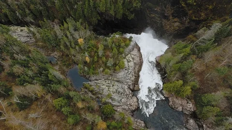 A drone camera approaches a waterfall between the shores with an autumn forest Stock-Footage 126077777