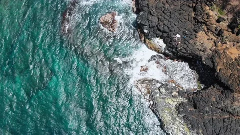 Drone camera approaching the waves of the ocean foaming off the rocky shore Stock Footage 135917894