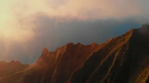 Drone camera captures a panorama of a sunlit ocean and golden mountain peaks Video stock 138237685