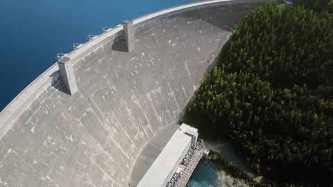 Drone camera circles over a reservoir in front of a dam near a dense forest Video stock 123392736