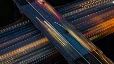 Drone camera-down nightlapse over busy freeway interchange at night Stock Footage