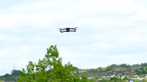 Drone with a camera flies against the background of trees and sky Stock Footage 321241490