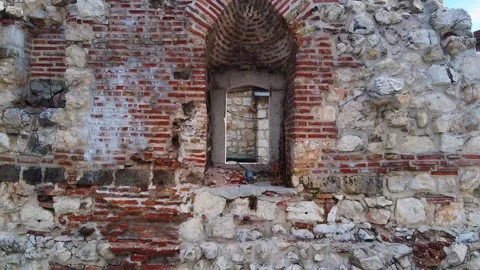 Drone with camera flies away from dilapidated window in wall of ruins of ancient Stock Footage 155769849