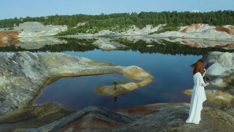 Drone camera flies over the quarry mountain where a violinist in white long dres 스톡 동영상 222536223